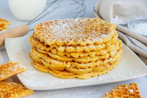 Ein Stapel goldbrauner Waffeln, bestäubt mit Puderzucker. Diese waffel ohne zucker sind perfekt für ein leichtes Frühstück.