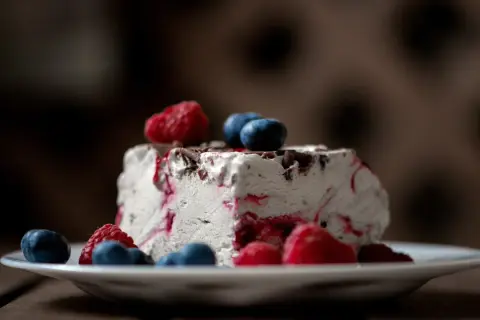 Ein Stück Eistorte mit Beeren und Schokostückchen, perfekt für ein einfaches Eistorte Rezept.