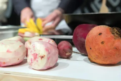 Bunte Bete, frisch geschält und bereit für die Zubereitung. Eine rote und eine orangefarbene Bete liegen daneben.