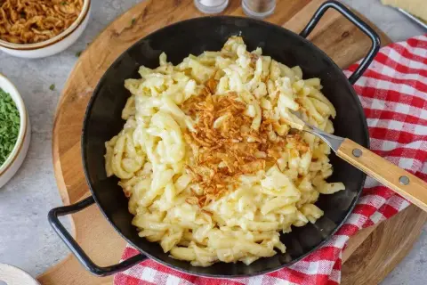 Herzhafte Käsespätzle mit knusprigen Röstzwiebeln, perfekt, um Sahne zu verwerten.