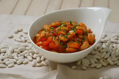 Schmackhafte weiße Bohnen in Tomatensoße, garniert mit Schnittlauch. Die Frage "wie lange bohnen kochen" wird hier visuell beantwortet: Sie sind perfekt gegart und servierfertig.
