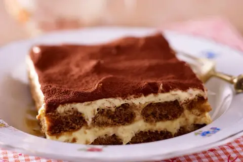 Ein Stück cremiges Tiramisu, das klassische italienische Dessert, bestäubt mit Kakao.