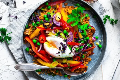 Buntes Reisgericht mit Gemüse und pochiertem Ei. Eine schnelle und leckere Idee, was man zu Reis essen kann.