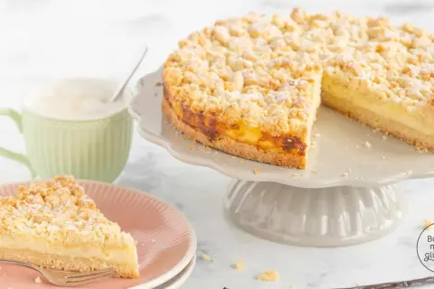 Ein köstlicher Pudding Streuselkuchen mit einer cremigen Füllung und knusprigen Streuseln, daneben eine Tasse Kaffee.