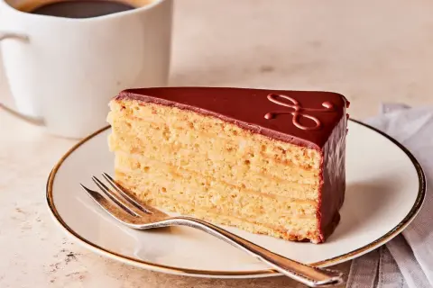 Ein Stück Schokoladenkuchen mit vielen Schichten, perfekt für ein Herrentorte Rezept. Dazu eine Tasse Kaffee.