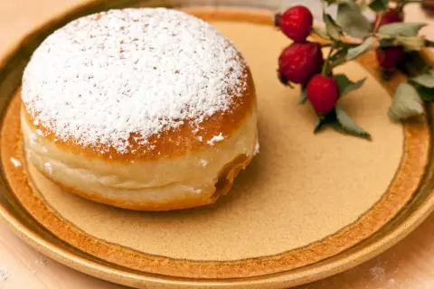 Ein mit Puderzucker bestäubter Krapfen liegt auf einem Teller. Daneben ein Zweig mit Hagebutten. Was ist Hiffenmark?