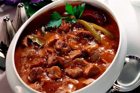 Herzhaftes Pfefferpotthast Rezept in einer Schüssel, garniert mit Petersilie und Gewürzgurken. Ein Klassiker der westfälischen Küche.