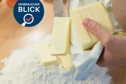 Verbraucherblick: Welche Butter ist die beste? Ein Messer schneidet Butter, die auf Mehl liegt.