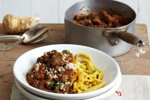 Zartes Gulasch mit Spätzle, garniert mit frischer Petersilie und geriebenem Meerrettich. So wird Gulasch zart!