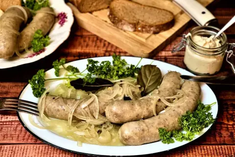 Herzhafte Würste mit Zwiebeln und Petersilie, serviert mit Brot und Dip. Was sind blaue Zipfel? Diese Würste sind ein Genuss!