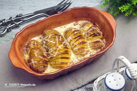 Gerichte mit Kartoffeln: Hasselback-Kartoffeln in cremiger Sauce, goldbraun gebacken und mit Käse überbacken, serviert in einer Auflaufform.