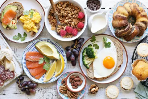 Leckere Brunch Ideen warm: Rührei, Lachs-Avocado-Toast, Müsli, Obst, Kuchen und Gebäck.