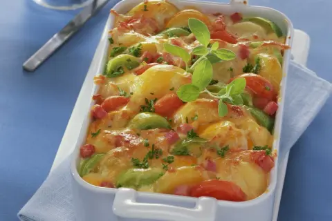 Herzhaftes Kartoffel Lauch Gratin mit Tomaten und Speck, überbacken mit goldbraunem Käse und garniert mit frischen Kräutern.