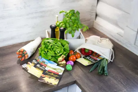 Frische Zutaten wie Salat, Tomaten, Paprika und Kräuter, dazu Käse und ein Osterhase – alles da, um Lebensmittelverschwendung zu vermeiden und leckere Mahlzeiten zu zaubern.