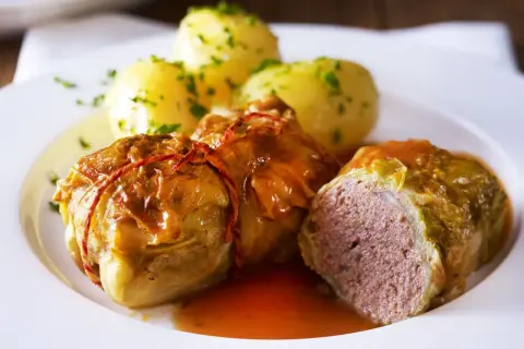 Herzhafte Kohlrouladen mit Kartoffeln, ein Klassiker der deutschen Gerichte, serviert auf einem weißen Teller.
