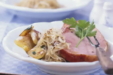 Herzhaftes Fleisch zu bayrisch Kraut mit Bratkartoffeln, garniert mit Petersilie. Ein Klassiker der bayerischen Küche.