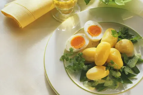 Ein einfaches zuckerschoten rezept: Salzkartoffeln, hartgekochte Eier und Zuckerschoten mit Kräutersauce auf einem Teller.