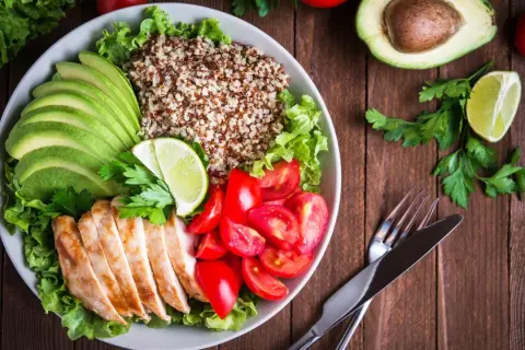 Schüssel mit Quinoa, Hähnchenbrust, Avocado, Tomaten und Salat. Ein leicht verdauliches Essen, das gut aussieht und schmeckt.