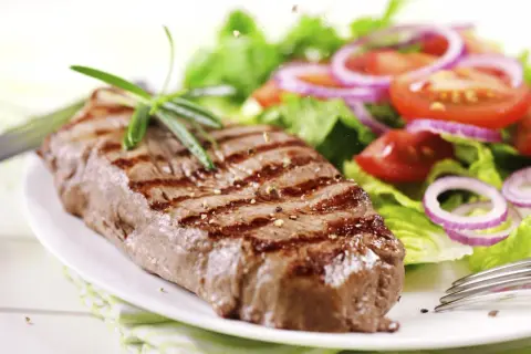 Saftiges Steak mit Grillstreifen und frischem Salat. Perfekt gegart, um zu wissen, wie lange steak im ofen nachgaren muss.