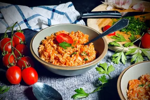 Ein einfacher Tomatenreis, garniert mit frischer Petersilie und Tomaten. Perfekt für ein schnelles und leckeres Abendessen.