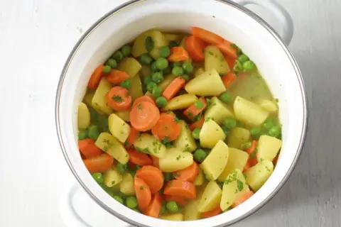 Ein Topf mit Kartoffeln, Karotten und Erbsen, ein einfaches und leckeres erbsen rezept.
