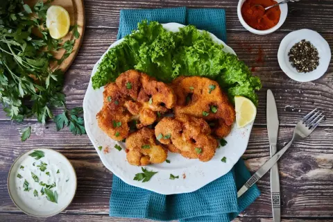 Knuspriges Blumenkohl Schnitzel mit frischem Salat, Zitrone und Dip. Ein Genuss für Vegetarier!
