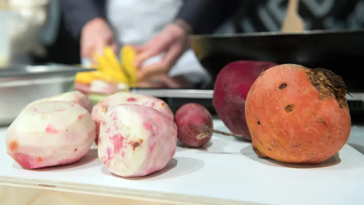 Bunte Bete, frisch geschält und bereit für die Zubereitung. Eine rote und eine orangefarbene Bete liegen daneben.