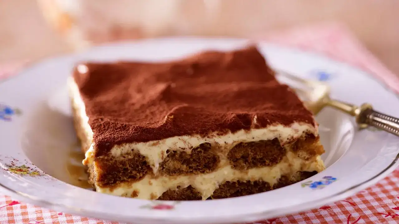 Ein Stück cremiges Tiramisu, das klassische italienische Dessert, bestäubt mit Kakao.