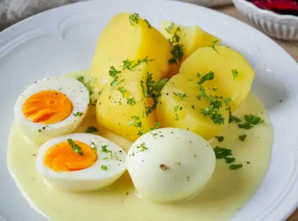 Saure Eier Rezept: Gekochte Eier und Kartoffeln in cremiger Sauce, garniert mit Petersilie. Ein einfaches und leckeres Gericht.