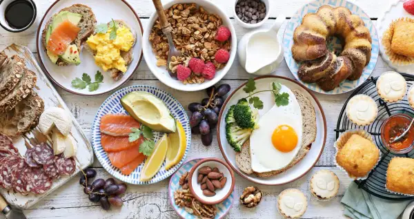 Leckere Brunch Ideen warm: Rührei, Lachs-Avocado-Toast, Müsli, Obst, Kuchen und Gebäck.