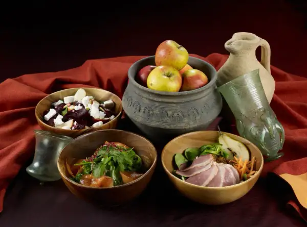 Essen wie im Mittelalter: Schalen mit Rote-Bete-Salat, Fleisch und Obst, dazu ein antiker Krug und Glas.