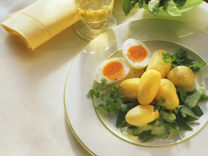 Ein einfaches zuckerschoten rezept: Salzkartoffeln, hartgekochte Eier und Zuckerschoten mit Kräutersauce auf einem Teller.